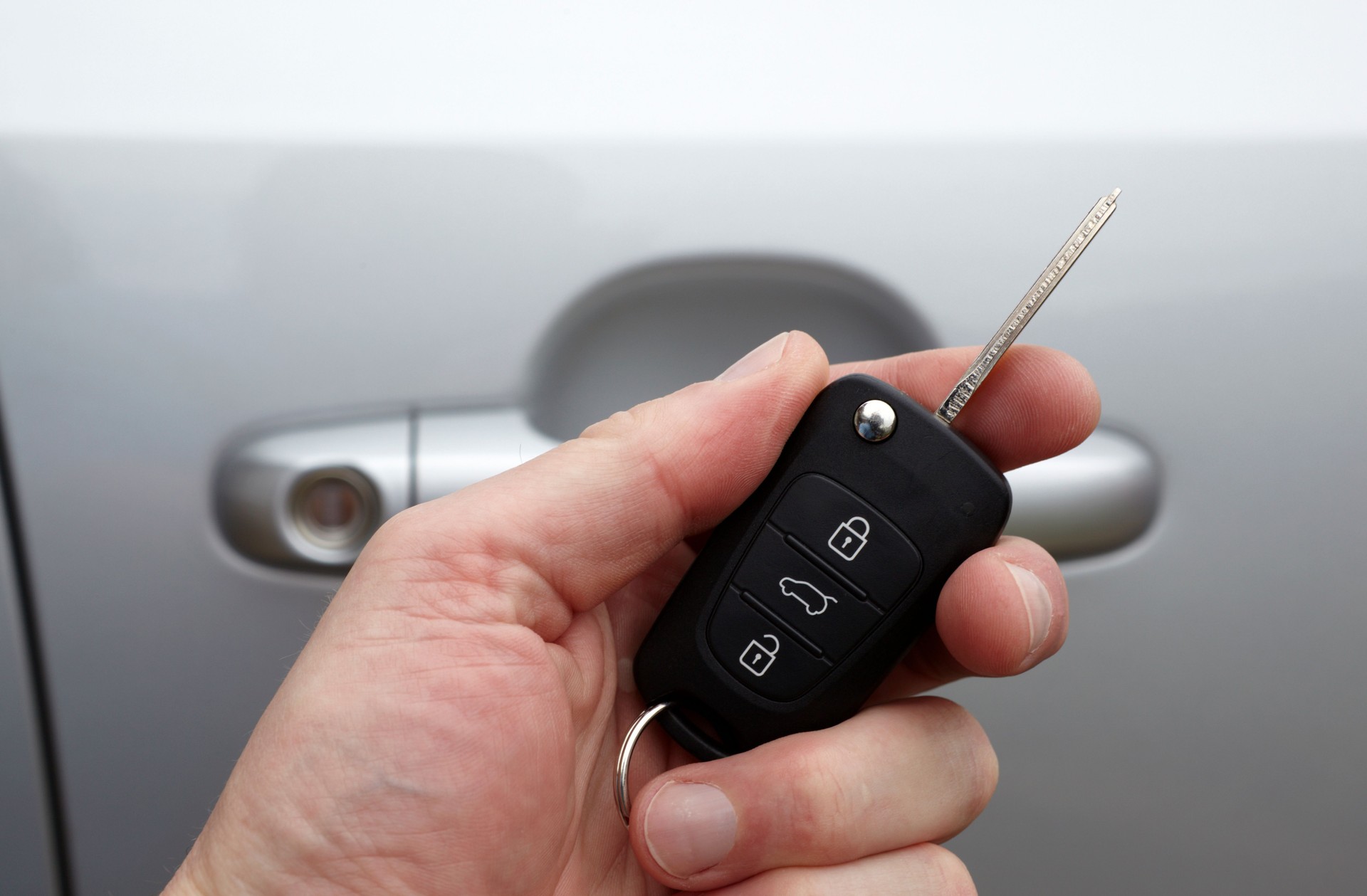 Holding Car Key in Hand with silver door at background